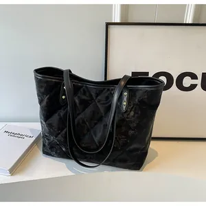 Close-up of black quilted tote bag with metallic vintage texture and slim straps