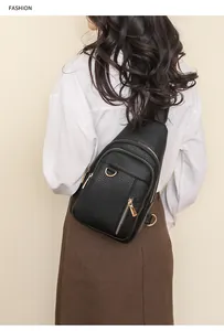 Rear view of model wearing a black litchi pattern chest bag with gold metal zippers