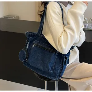 Dettaglio della borsa tote in denim blu scuro con tasca anteriore e piccolo borsellino tondo