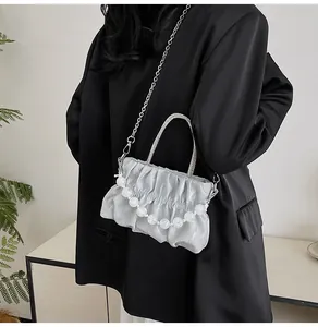 Detailed view of silver metallic pleated handbag with pearl chain and metal handle
