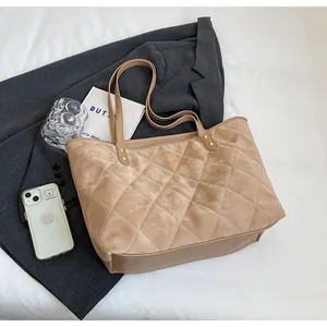 Detail view of khaki quilted velvet tote with diamond stitching and gold rivet accents