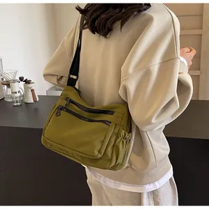 Detailed side view of olive green nylon crossbody bag with dual front zippers and drawstrings
