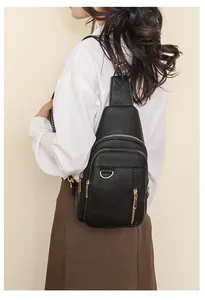 Detail of black pebbled leather chest bag with zipper pockets and metal D-ring decoration