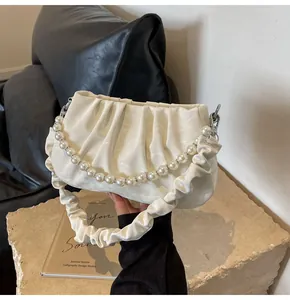 Close-up of pleated white cloud bag with elegant pearl chain and silver hardware detail