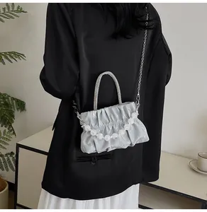 Detail of pleated cloud bag with rhinestone handle and pearl chain on a stylish model