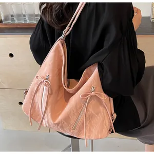 Pink tote bag with unique crinkled texture, side zippers, and decorative ribbon details