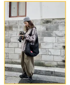 Detail view of durable black canvas hobo bag with signature red square label