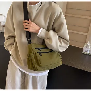 Detail of dark green nylon crossbody bag with dual front zippers and side pockets