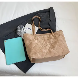 Detail of diamond quilted suede tote bag showing soft texture and reinforced metal rivets
