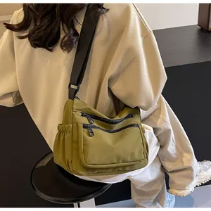 Close-up of olive green nylon crossbody bag showing multiple zippers and side pocket
