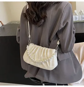 Detail of white pleated cloud bag with pearl chain shown on dark grey blazer