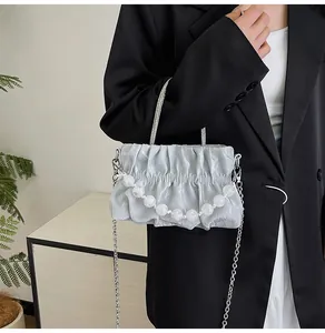 Detail of silver pleated cloud bag with marble bead handle and metallic chain strap
