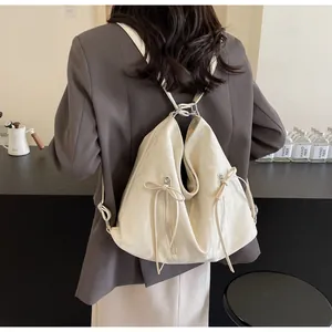 Close-up of cream PU leather backpack with delicate zipper details and leather bow accents