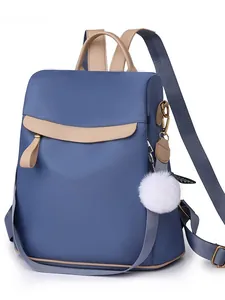 Sac à dos en nylon bleu-gris avec garniture marron clair et pompon blanc sur fond blanc