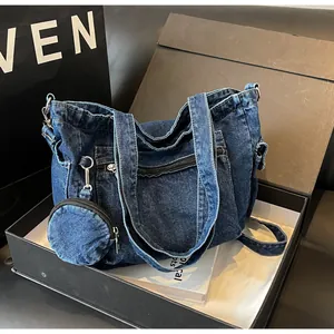 Dettaglio della borsa tote in denim blu scuro con tasche a zip e piccolo borsellino tondo