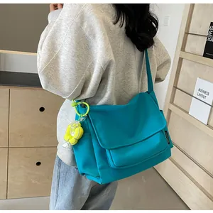 Blauwe canvas crossbodytas op model met een opvallende neongele bloemenhanger detail