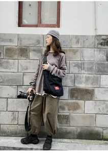Detail of gray distressed sweatshirt and large black canvas crossbody bag on a model