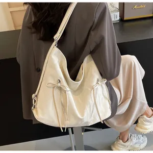 Detail of off-white hobo bag with metal zippers and decorative leather bow knot