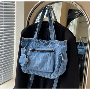Dettaglio della borsa tote in denim blu con tasca laterale e ciondolo portamonete abbinato
