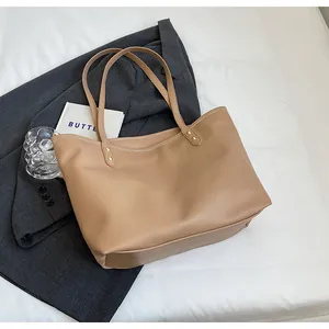 Detail of khaki quilted tote bag with long handles and golden stud accents on white fabric