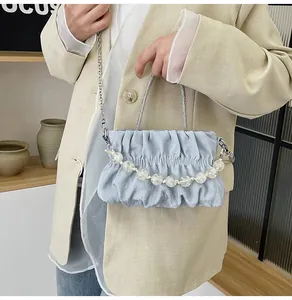 Detail of light blue pleated cloud bag with silver chain and decorative beads on model