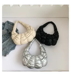 Close-up of quilted cloud bags in cream, black, and silver metallic faux leather