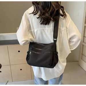 Detail of a large capacity nylon shoulder bag with multi-zipper pockets and side drawstring