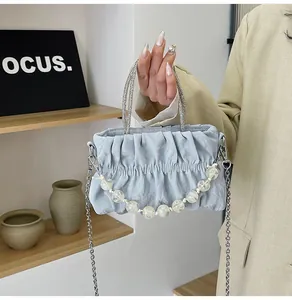 Close-up of light blue pleated cloud bag with diamond-encrusted metal handles and beads