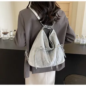 Detail of silver pleated leather backpack with bow accents and vertical zippers