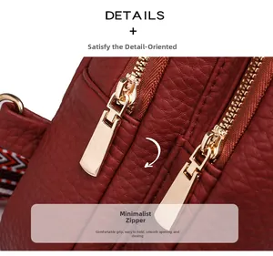 Close-up of smooth gold double zippers on red litchi texture leather crossbody bag
