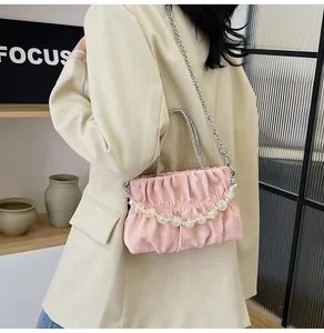 Detail of pink pleated handbag featuring pearl chain and metallic woven handle