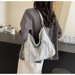 Detail of silver tote bag showing crinkled texture and dual bow zipper design