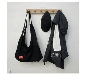 Detail of minimalist black canvas tote bag with red brand label hanging on wooden hook
