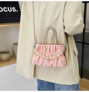 Detailed view of pink pleated handbag with sparkling rhinestone handle and beaded chain