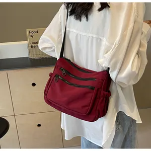 Red nylon crossbody bag with multi-layer zippers and adjustable strap on person
