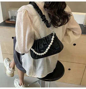 Detail der eleganten schwarzen Raff-Tasche mit dekorativer Perlenkette am Schulterriemen