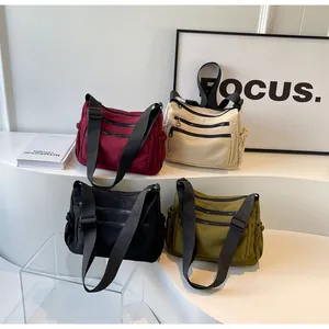 Collection of nylon crossbody bags in burgundy, cream, black, and olive green on white podiums