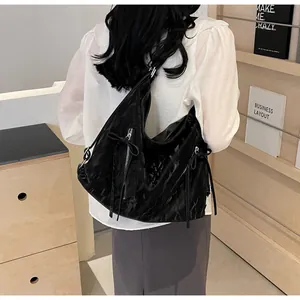 Black glossy pleated hobo bag with metal zipper and ribbon detail worn by model