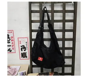 Detail of a black nylon crescent crossbody bag with adjustable strap and red brand tag