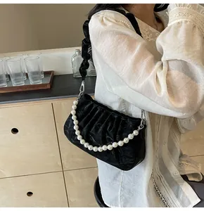 Detailed close-up of a black pleated cloud bag with elegant white pearl decorative chain