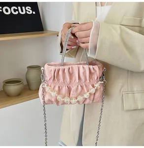 Detail of pink pleated bag with faux pearl accents and a crystal-encrusted handle