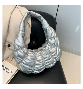 Detail view of silver quilted cloud bag with metallic ruched texture on a leather seat
