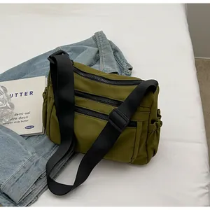 Detail of olive green nylon crossbody bag with multi-layer zippers and side pocket