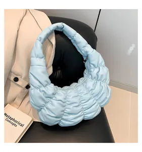 Detail of light blue ruched cloud bag showing quilted texture on a leather seat