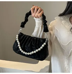 Close-up of black velvet pleated cloud bag featuring large pearl chain and silver hardware