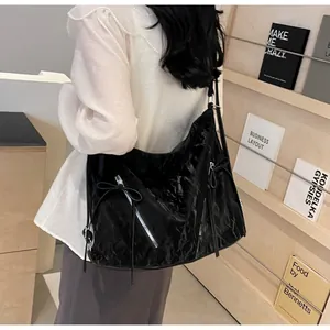 Detail view of the black wrinkled leather texture with silver zipper and bow on tote bag