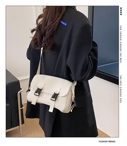 Minimalist cream white messenger bag with black buckle closure shown on model