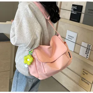 Detail van roze nylon crossbodytas met bloemenbedel en verstelbare schouderband
