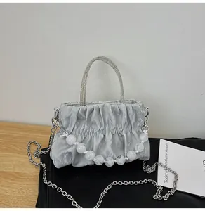Detail of silver pleated cloud bag with rhinestone handle and pearl decorative chain