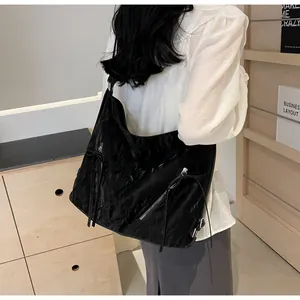 Detail of black hobo bag with pleated texture, silver zipper and bow tassel charm